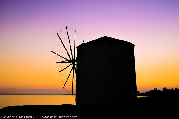 Silhouette of a Greek windmill at sunset Picture Board by Nic Croad