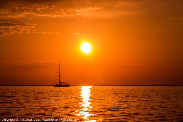Yacht on the sea at sunset Picture Board by Nic Croad