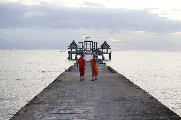 Thai monks on the bridge or Pier , which leads to the never finished and abandoned Thai temple right on the Gulf in Thailand in the province of Chonburi Picture Board by Wilfried Strang