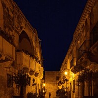 Buy canvas prints of Dramatic Narrow street by Night located in Gozo Ma by Maggie Bajada