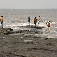 Buy canvas prints of Group of Indian students stand on rocks at Mumbai as the tide comes in by Gordon Dixon