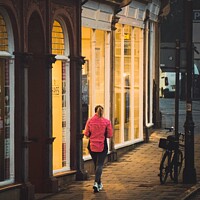 Buy canvas prints of A jogger passing a warm shop front  by Rowena Ko