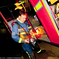 Buy canvas prints of Firefighter in breathing apparatus and fire appliance with blurred lights at a fire by Rose Sicily