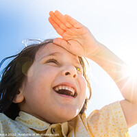 Buy canvas prints of Happy smiling boy in flare sunshine with  hand at forehead by Turgay Koca
