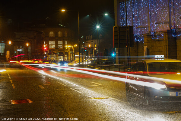 During the Evening of a Rainy Night, a Yellow Taxi Travels Along a Wet Road. Picture Board by Steve Gill
