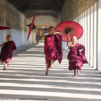 Buy canvas prints of Novice monks with umbrellas running at temple, Bagan, Myanmar by Matteo Colombo