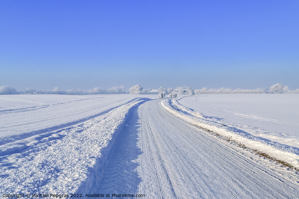 View of a snow-covered country road in winter with sunshine and blue sky Picture Board by Michael Piepgras