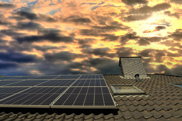 Solar panels producing clean energy on a roof of a residential house during sunset. Picture Board by Michael Piepgras