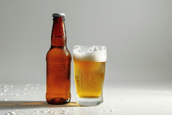 A bottle of beer and a filled glass on a white background. Picture Board by Michael Piepgras