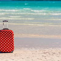 Buy canvas prints of Red polka dot travel luggage on sand beach by Spotmatik 