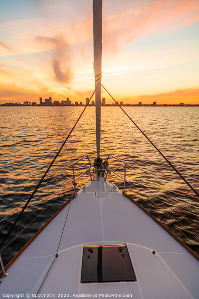 Bow of yacht sailing towards cityscape at sunrise Picture Board by Spotmatik 