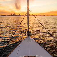 Buy canvas prints of Bow of yacht sailing towards cityscape at sunrise by Spotmatik 