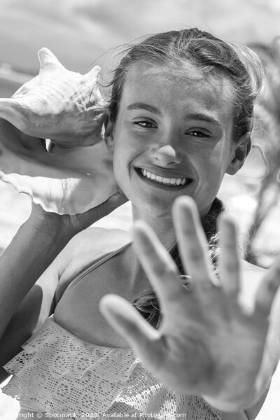 Portrait of young female listening seashell on beach Picture Board by Spotmatik 