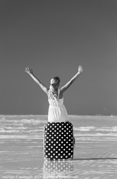 Blonde female teenager on beach sitting on suitcase Picture Board by Spotmatik 