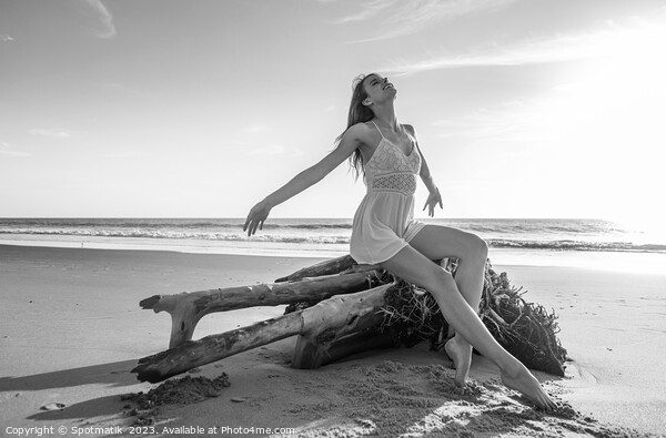 Young beach girl enjoying sun sitting on driftwood  Picture Board by Spotmatik 