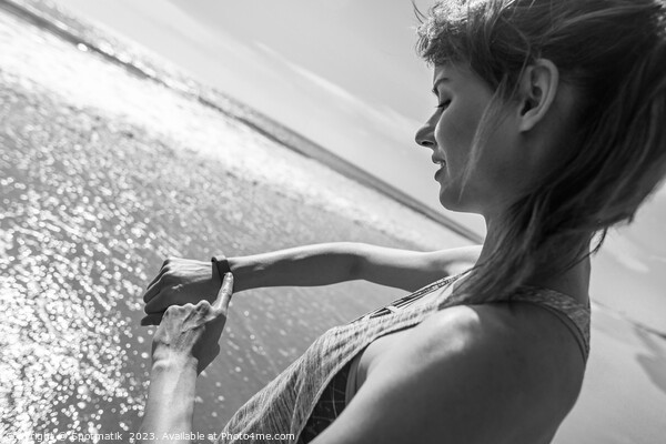 Caucasian female on ocean edge checking sports watch Picture Board by Spotmatik 
