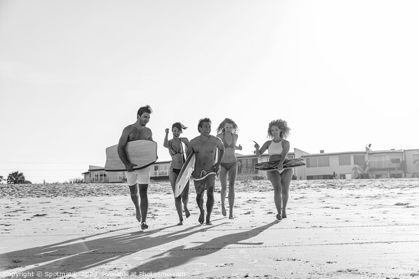Friends in swimwear running carrying bodyboards on beach Picture Board by Spotmatik 
