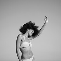 Buy canvas prints of Afro girl in swimwear dancing on the beach by Spotmatik 
