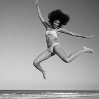 Buy canvas prints of Fun loving Afro female jumping by the ocean by Spotmatik 