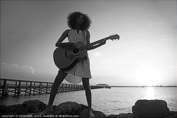 Young African American woman playing guitar at sunrise Picture Board by Spotmatik 