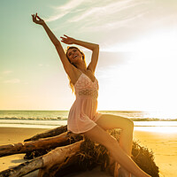 Buy canvas prints of Carefree Bohemian girl sitting on driftwood at sunset by Spotmatik 