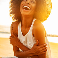 Buy canvas prints of Laughing Afro American female wearing hat on beach by Spotmatik 