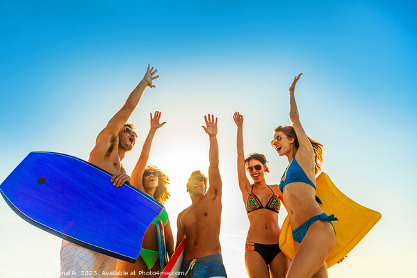 Friends in swimwear carrying bodyboards celebrating fun activity Picture Board by Spotmatik 