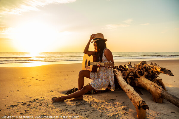 Indian female sitting on driftwood with ocean sunrise Picture Board by Spotmatik 