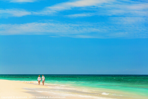 Mature couple walking along shoreline at beach resort Picture Board by Spotmatik 
