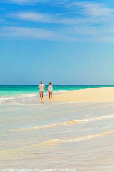 Mature couple walking on beach by ocean Bahamas Picture Board by Spotmatik 