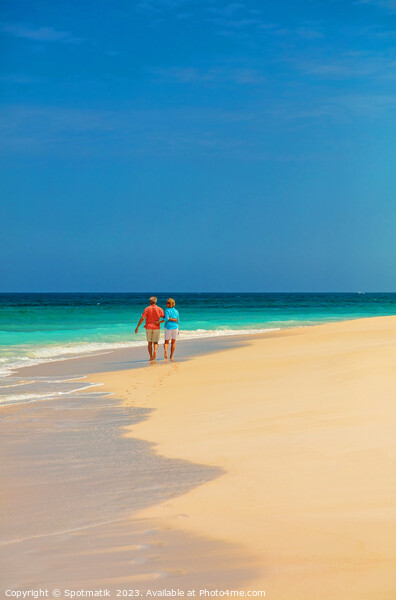 Tropical island shoreline with retired couple walking barefoot Picture Board by Spotmatik 