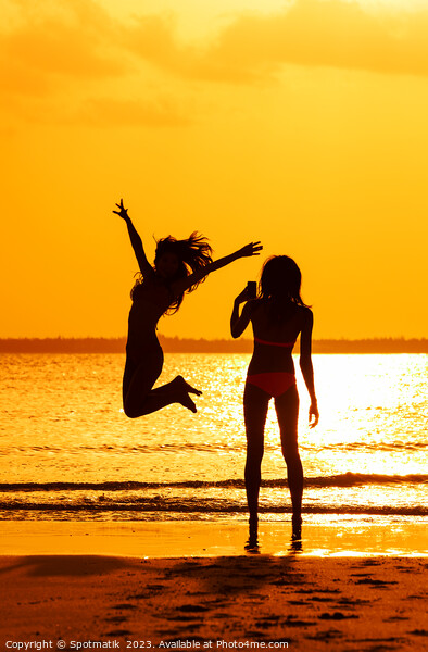 Tropical ocean sunrise with girl photographing friend jumping Picture Board by Spotmatik 