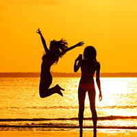 Buy canvas prints of Tropical ocean sunrise with girl photographing friend jumping by Spotmatik 