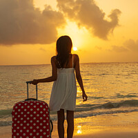 Buy canvas prints of Young woman with suitcase enjoying tropical ocean sunrise by Spotmatik 