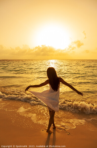 Asian girl standing in ocean waves at sunrise Picture Board by Spotmatik 
