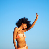 Buy canvas prints of Afro girl in swimwear dancing on the beach by Spotmatik 
