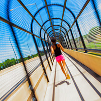 Buy canvas prints of Young Afro American woman running through covered walkway by Spotmatik 