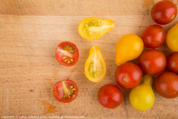 Red and yellow cherry tomatoes on a wooden cutting board Picture Board by Lubos Chlubny