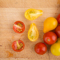 Buy canvas prints of Red and yellow cherry tomatoes on a wooden cutting board by Lubos Chlubny