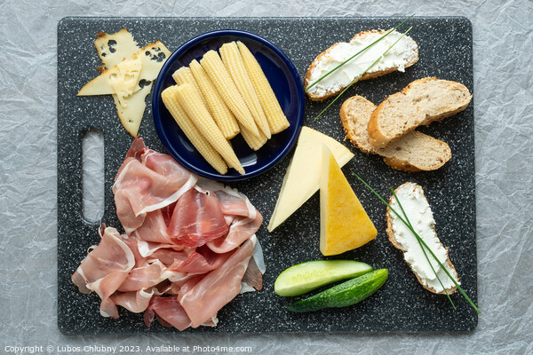 Cold appetizer. Cold cuts. Spicy food on black background, top view. Picture Board by Lubos Chlubny