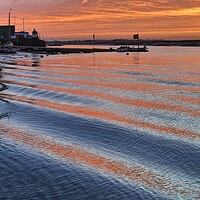 Buy canvas prints of Sunrise reflections over er the passing wakes at Brightlingsea Harbour by Tony lopez