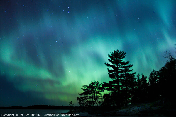 Northern lights erupt over a lake in Minnesota in a dark sky ove Picture Board by Rob Schultz