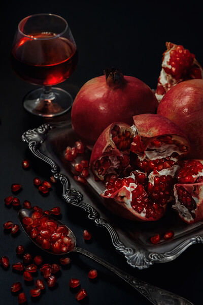 Still life of pomegranates on a black background Picture Board by Olga Peddi