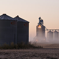Buy canvas prints of grain storage bins in a harvested soybean field with inland grain terminal in the background by Dave Reede