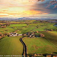 Buy canvas prints of Aerial view of a picturesque village amidst green fields during sunset with a vibrant sky and a meandering river. by Man And Life