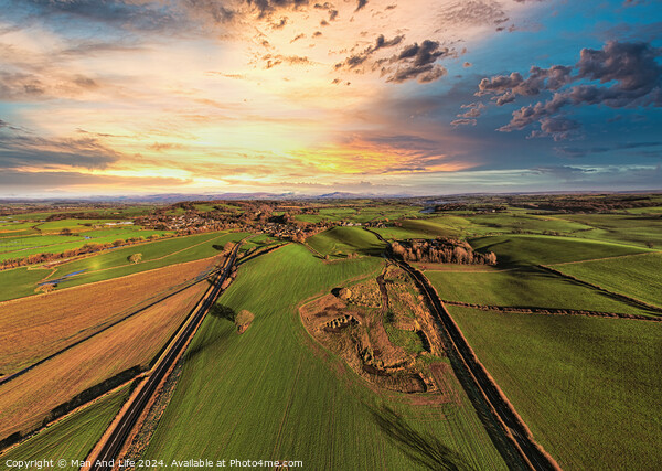 Aerial view of a lush countryside at sunset with vibrant skies and patchwork fields. Picture Board by Man And Life