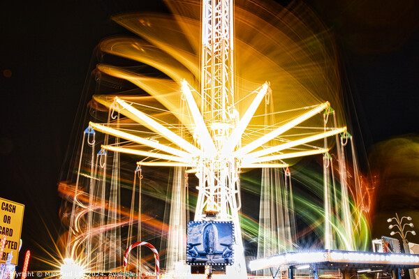 Long exposure of a brightly lit carousel at night, capturing motion blur of spinning lights at a fair. Picture Board by Man And Life