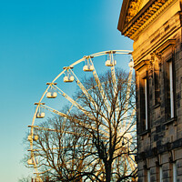 Buy canvas prints of Historic building corner with a Ferris wheel and tree silhouettes against a clear blue sky at sunset in Lancaster. by Man And Life