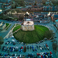 Buy canvas prints of Aerial view of a historic building with a circular shape surrounded by a green lawn, parking area, and cityscape during twilight in York, North Yorkshire by Man And Life