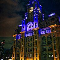 Buy canvas prints of Liverpool's iconic Royal Liver Building at night, illuminated with blue lights against a dark sky. by Man And Life